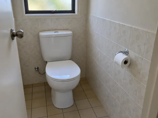 Clean white toilet in a tiled bathroom with a small window in Blacktown